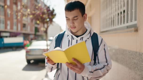 Молодой Человек Читает Книгу Стоя Улице — стоковое видео