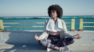 African american woman wearing sportswear doing yoga exercise at seaside