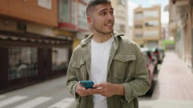 Sokakta akıllı telefon kullanan, kendine güvenen genç bir İspanyol.
