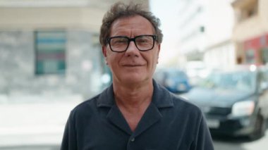 Orta yaşlı bir adam, Kanada pasaportunu göstererek sokağı işaret ediyor.