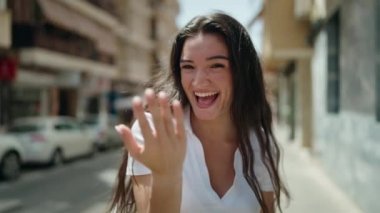 Genç İspanyol kadın gülümsüyor. Kendinden emin. Sokakta el kol hareketi yapıyor.