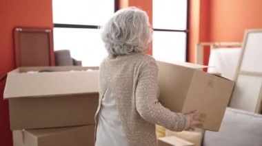 Orta yaşlı, gri saçlı, kendine güvenen, yeni evinde dans eden bir kadın.