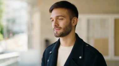 Young hispanic man with relaxed expression standing at street