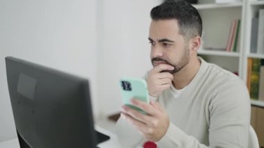 Kütüphanede bilgisayar ve akıllı telefon kullanan genç İspanyol öğrenci.