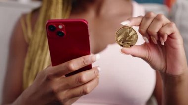 Evde akıllı telefon kullanarak litekoin kripto parası tutan Afrikalı Amerikalı bir kadın.