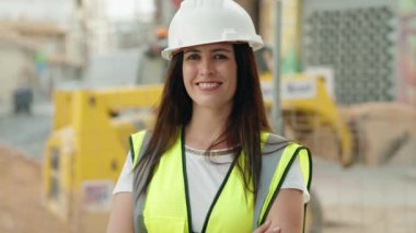 Güzel İspanyol kadın mimar gülümsüyor. Kollarını kavuşturup caddede duruyor.