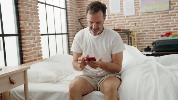 Middelbare Leeftijd Man Met Behulp Van Smartphone Zitten Bed Slaapkamer — Stockvideo