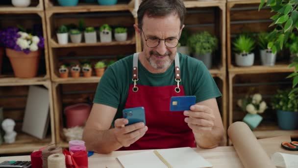 花屋でクレジットカードを保持スマートフォンを使用している中年の男の花屋 — ストック動画