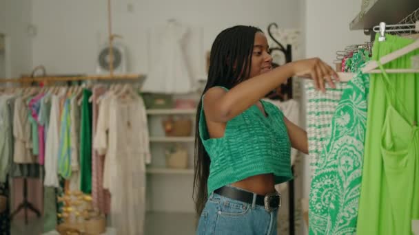 アフリカ系アメリカ人女性の顧客は衣料品店で服ラックを見て — ストック動画