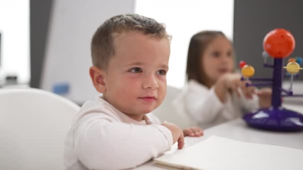 可爱的女孩和男孩在幼儿园坐在桌面上学习行星 — 图库视频影像