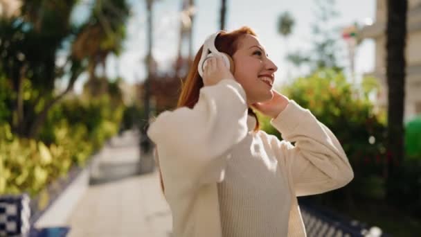 Młoda Ruda Kobieta Uśmiecha Się Pewnie Słuchając Muzyki Parku — Wideo stockowe