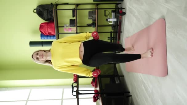 Genç Sarışın Kadın Spor Merkezinde Dambıl Kullanarak Bacak Egzersizi Yapıyor — Stok video