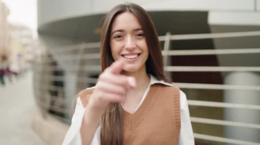 Genç İspanyol kadın gülümsüyor. Kendinden emin. Sokakta jest yapıyor.