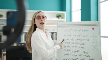 Young blonde woman teacher explaining online maths exercise at library university