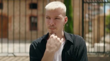 Sokakta şüpheli bir ifadeyle duran genç beyaz bir adam.