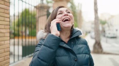 Orta yaşlı bir kadın akıllı telefondan konuşuyor. Sokakta nöbet tutuyor.