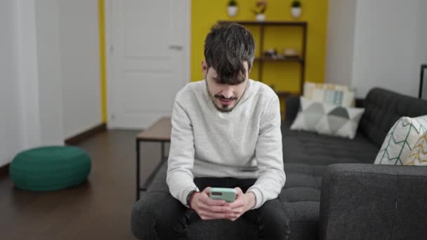 Young Hispanic Man Using Smartphone Doing Gesture Home — Vídeo de Stock