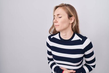 Genç beyaz kadın, mide bulantısı, acı verici bir hastalık yüzünden eli karnında sıradan bir kazak giyiyor. Ağrı kavramı. 