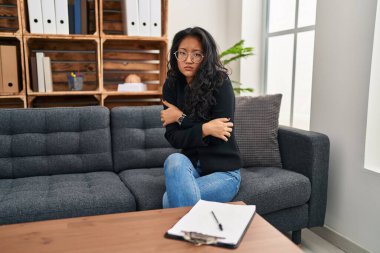 Muayenehanedeki genç Asyalı kadın yüzünde üzgün ve şok ifadesiyle kış soğuğu yüzünden titriyor ve donuyor. 