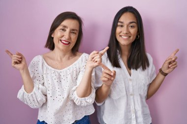 İspanyol anne ve kızı birlikte gülümseyerek parmaklarıyla farklı yönleri işaret ediyorlar. reklam için kopyalama alanı 