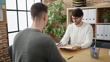 İki erkek iş ortağı ofiste sözleşme imzalıyor.