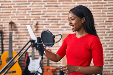 Young african american woman artist singing song at music studio