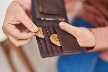 Middle age woman holding bitcoin of leather wallet at home clipart