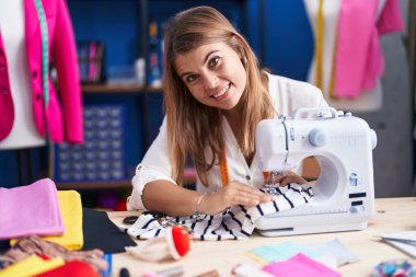 Dikiş atölyesinde dikiş makinesi kullanan kendine güvenen genç bir terzi.