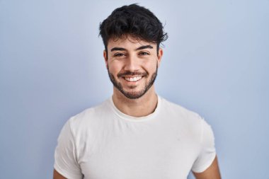 Hispanic man with beard standing over white background with a happy and cool smile on face. lucky person. 