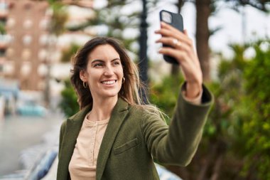 Young woman smiling confident making selfie by the smartphone at park