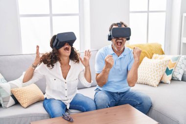 Kadın ve erkek evde sanal gerçeklik gözlüğü kullanarak video oyunu oynuyorlar.