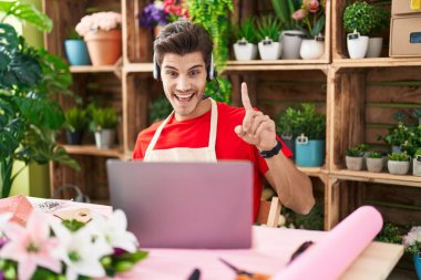 Çiçekçide çalışan İspanyol asıllı genç bir adam bir fikir veya soruyla gülümsüyor ve gülümsüyor. 