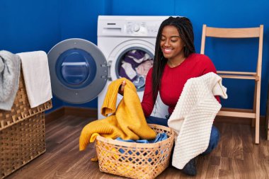 African american woman smiling confident washing clothes at laundry room