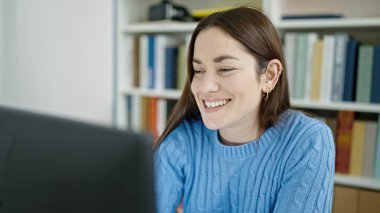 Kütüphanede bilgisayar eğitimi alan beyaz bir kız öğrenci.