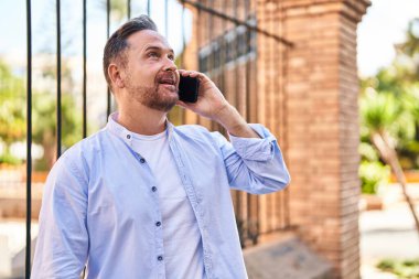 Kafkasyalı genç adam gülümsüyor. Kendine güvenen caddedeki akıllı telefondan konuşuyor.