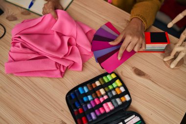 Young blonde woman dressmaker choosing cloth color at designer studio