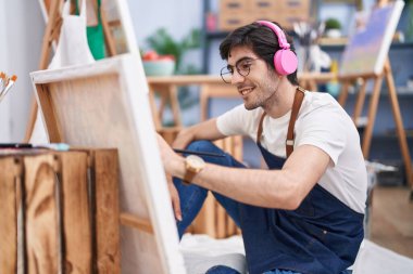 Genç İspanyol ressam resim stüdyosunda müzik dinliyor.