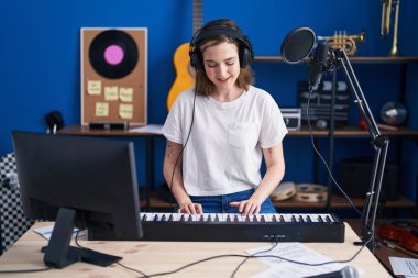 Young woman musician playing piano keyboard at music studio