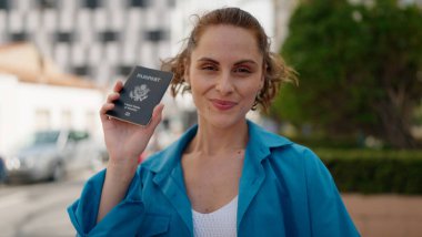 Young woman smiling confident holding united states passport at street