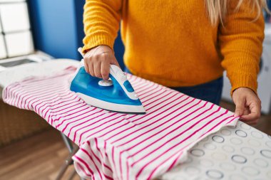 Çamaşır odasında ütü yapan genç ve güzel bir kadın.