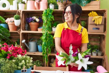 Young beautiful arab woman florist holding bouquet of flowers at flower shop