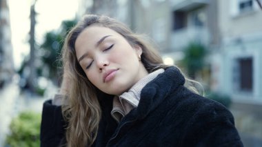 Young beautiful hispanic woman combing hair with hands at street