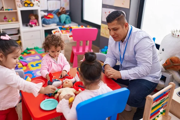 stock image Hispanic man and girls playing supermarket game sitting on table at kindergarten