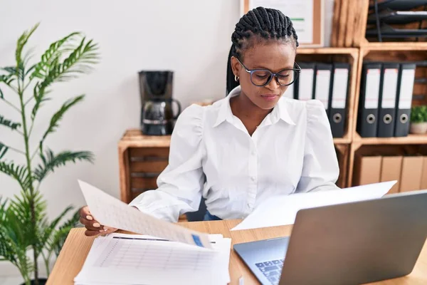 アフリカ系アメリカ人の女性ビジネスワーカーがオフィスでノートパソコン読み取り文書を使う — ストック写真