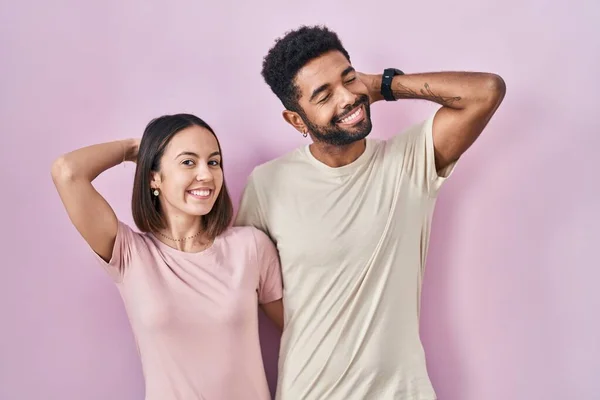 Jong Hispanic Paar Samen Roze Achtergrond Glimlachen Zelfverzekerd Aanraken Haar — Stockfoto