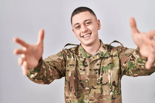 Молодой Человек Камуфляжной Армейской Униформе Смотрит Камеру Улыбаясь Распростертыми Объятьями — стоковое фото