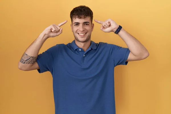 Young Hispanic Man Standing Yellow Background Smiling Pointing Head Both — 스톡 사진
