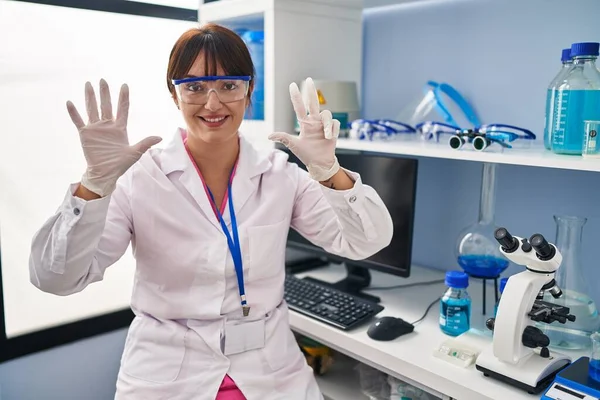 Jeune Femme Brune Travaillant Laboratoire Scientifique Montrant Pointant Doigt Numéro — Photo