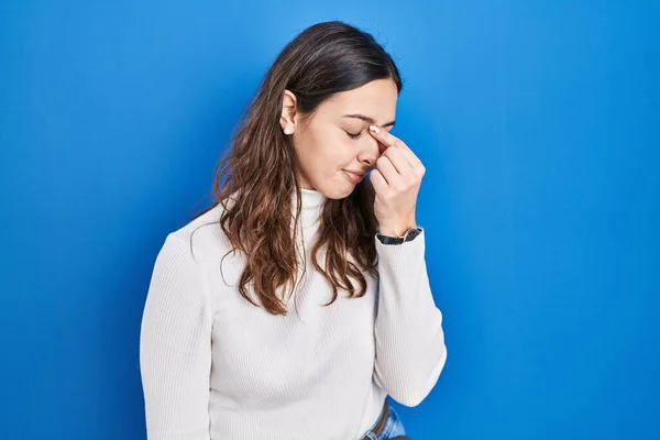青の背景に立っている若いヒスパニック系の女性疲れ鼻や目の疲労感や頭痛をこすり ストレスとフラストレーションの概念 — ストック写真