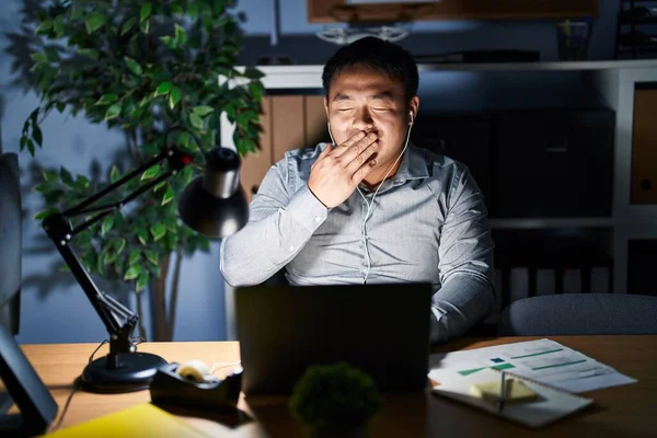 夜にコンピュータのラップトップを使用して作業している若い中国人男性は 手で口をカバー疲れあくび退屈 落ち着きもなく眠気もなく — ストック写真